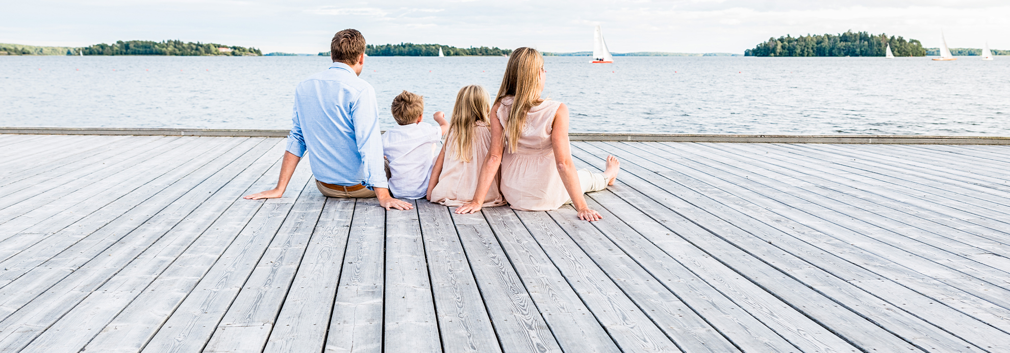 Perhe istuu laiturilla ja katselee merelle